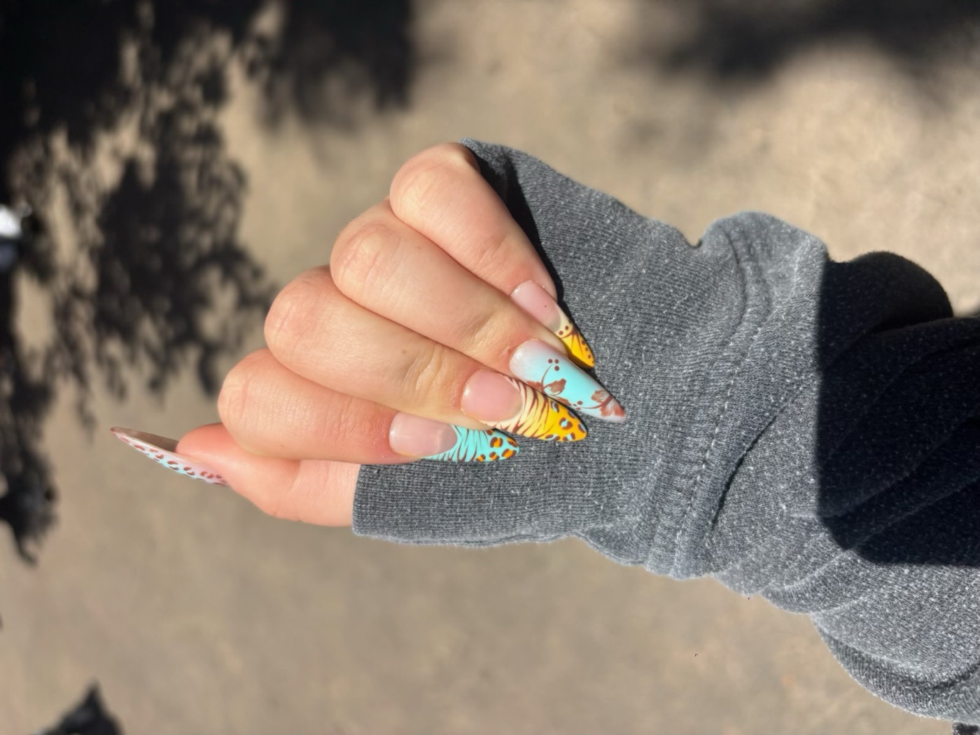 Long almond press-on nails in turquoise and orange animal print with hand-painted flowers